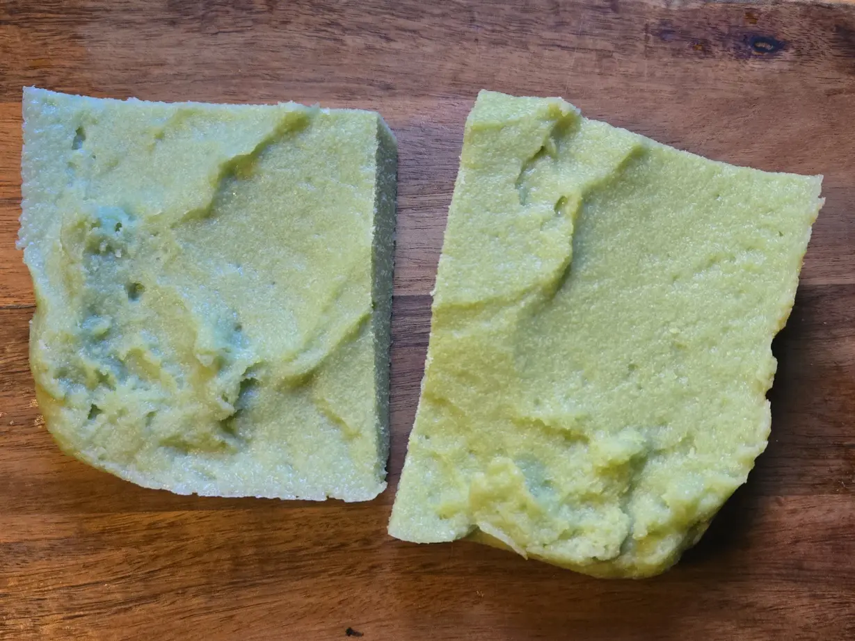 Two rectangular slabs of light green tofu on a wooden surface