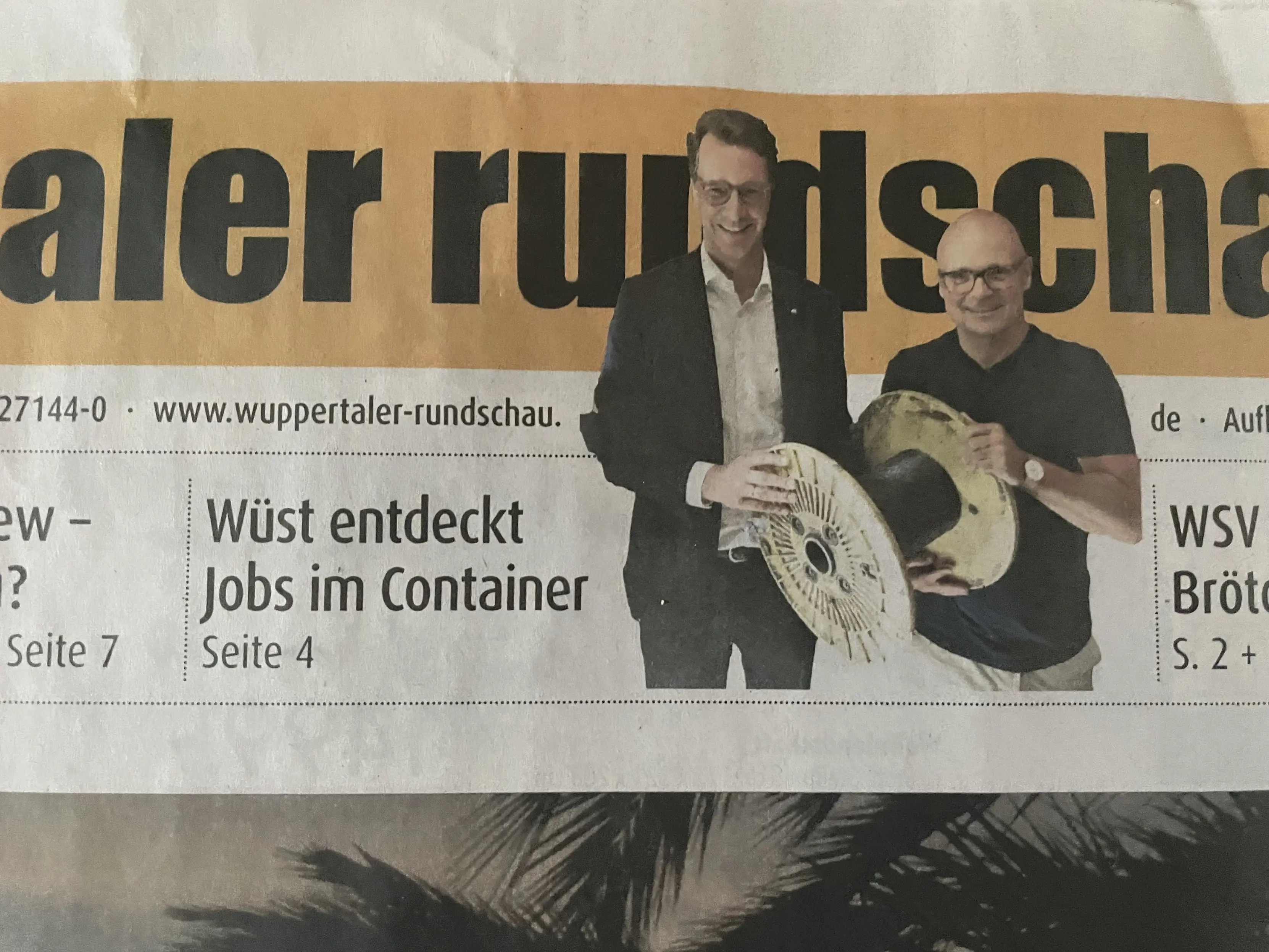 Ausschnitt des Titelblatts der Wuppertaler Rundschau mit der Schlagzeile „Wüst entdeckt Jobs im Container“. Daneben ein Freisteller von Ministerpräsident Wüst grinsend mit einer kleinen Kabeltrommel. 