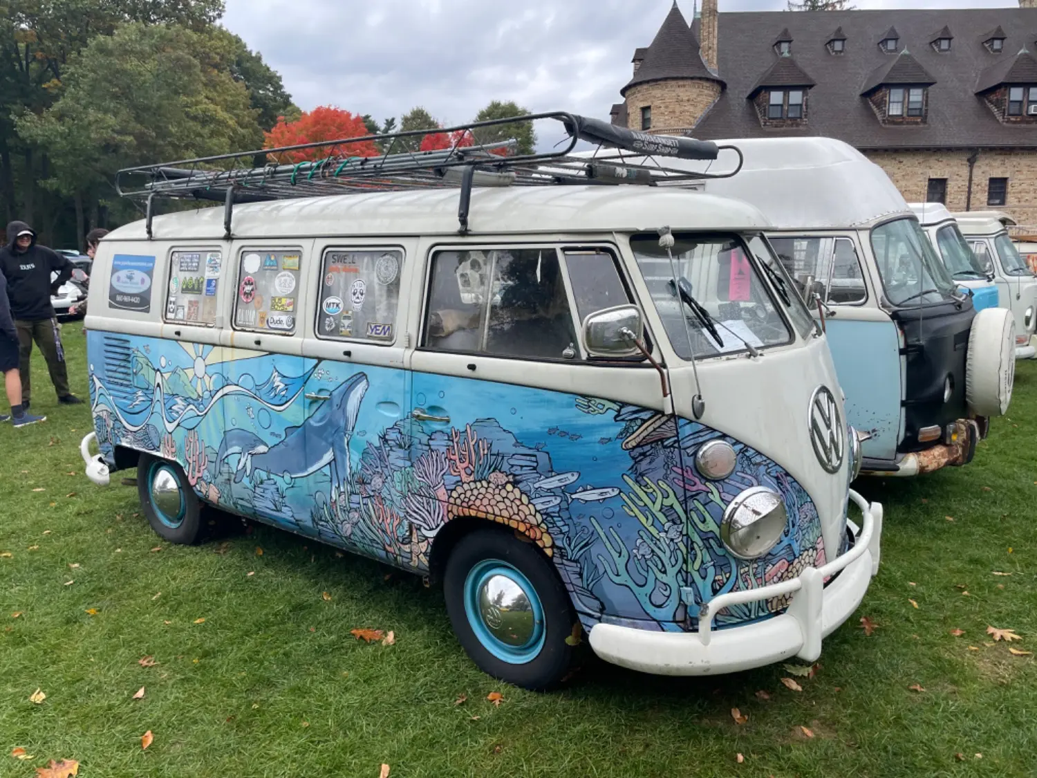 A blue and white VW Bus with a deep sea themed mural hand painted on the lower half of the bus. 