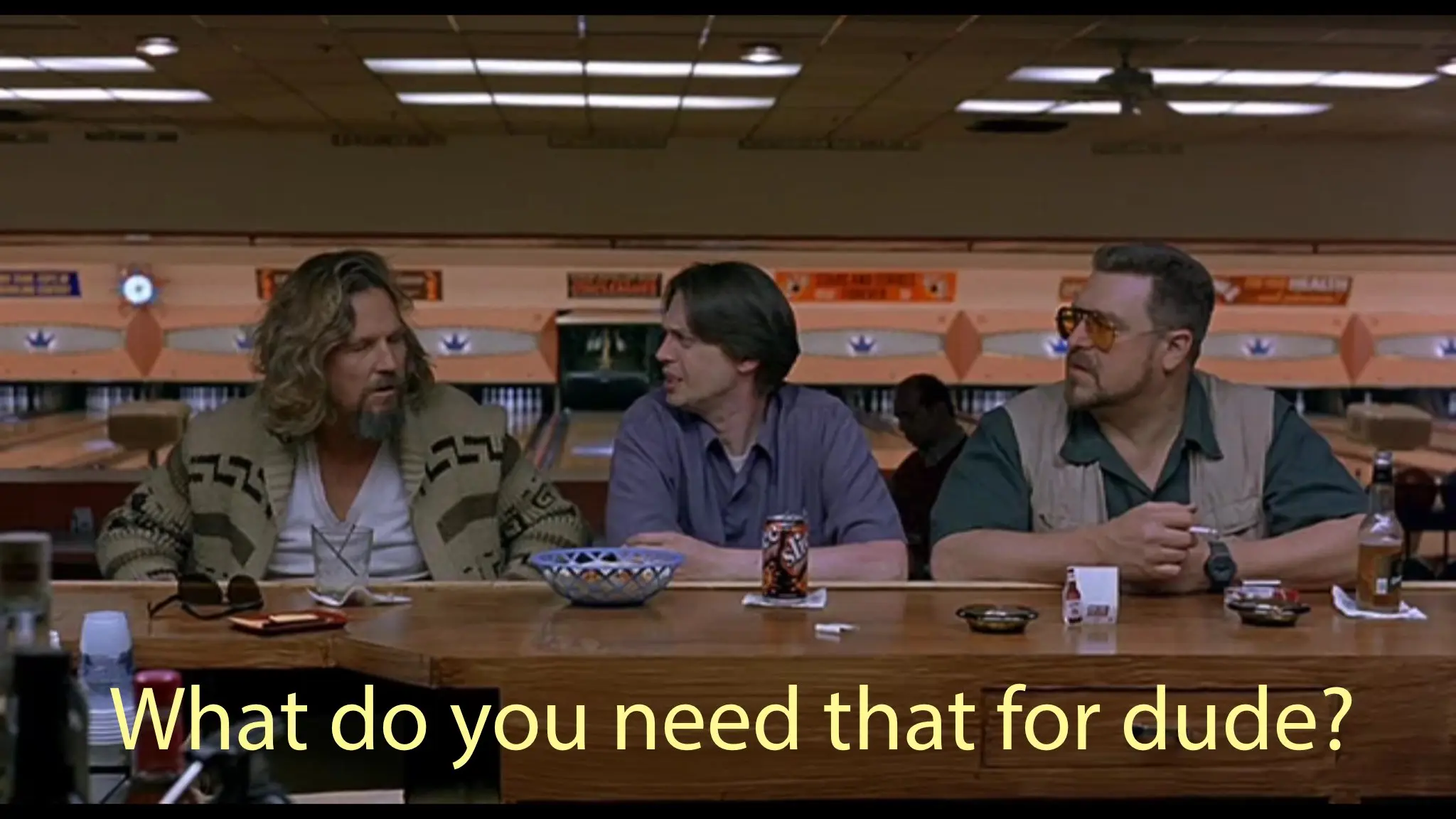 Screengrab from the movie, "The Big Lebowski". The Dude, Donny and Walter sit at the bar in the bowling alley. Text of Donny's dialogue from the scene is overlaid and reads, "What do you need that for dude?"